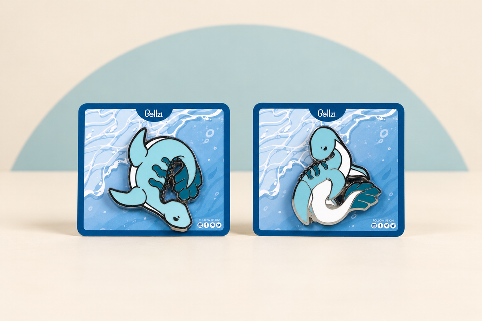 Nessi Enamel Pin - Dive and Nessi Enamel Pin - Flaunt on a cream background with a soft blue curve