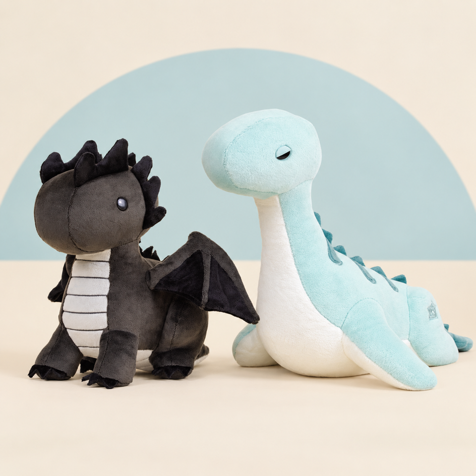 Black Draggi the Fire Dragon and Nessi the Loch Ness Monster on a cream background with a soft blue curve