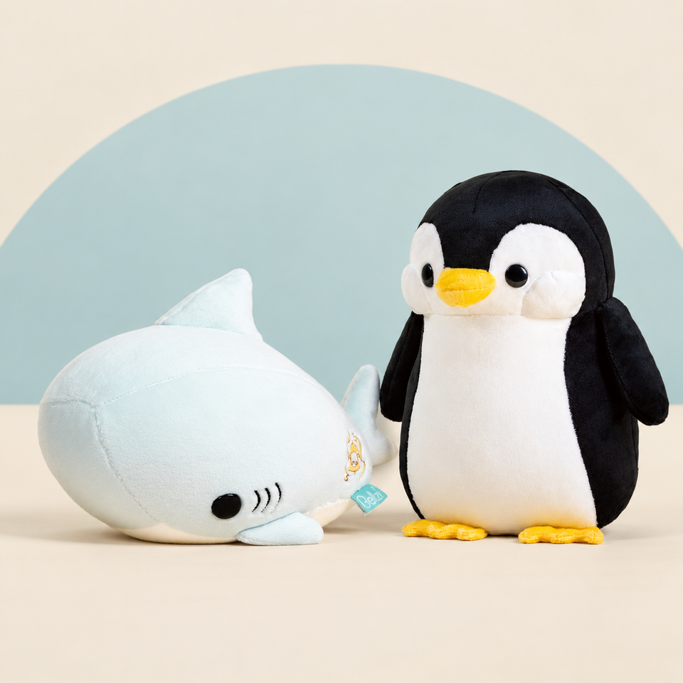 Sharki the Great White Shark and Pengi the Penguin on a cream background with a soft blue curve